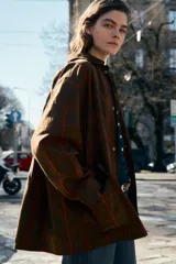 Chaqueta de mujer de la colección Zara Woman, confeccionada en algodón 100% con acabado encerado. Presenta un estampado a cuadros en tonos marrón y rojo, cuello solapa de pana, manga larga con puño y botón, bolsillos de plastrón con solapa en el delantero y cierre frontal con botones a presión.