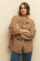 Abrigo gamulán de corderito color crudo, con alamares de cuero sintético negro y cierres metálicos.