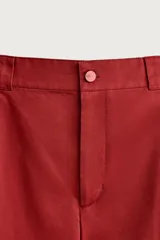 Pantalón wide fit color rojo terracota, con pliegues frontales, bolsillos laterales y cierre frontal con cremallera y botón.
