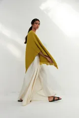 Ruana tejida color verde pistacho con flecos en el borde inferior y parche de cuero en la parte inferior.