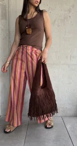 Pantalón de lino a rayas verticales en tonos rojo, naranja, marrón y rosa, con cierre y botón, y dos bolsillos laterales.