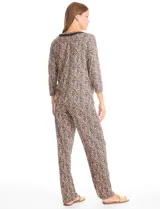 Conjunto de pijama compuesto por una remera de mangas largas con escote redondo y bolsillo frontal, y un pantalón largo con cintura elástica. Ambas piezas presentan un estampado floral y detalles de apliques de crochet en el cuello y el bolsillo.