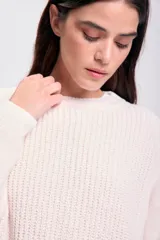Buzo de tejido de punto chenille en color crudo, con cuello redondo, mangas largas y puños acanalados. Presenta un diseño de textura combinada con paneles laterales de tejido liso y frente con textura de punto fantasía.