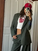 Blazer de sastrería con diseño oversize y hombreras pronunciadas. Presenta un estampado de rayas verticales finas, cierre frontal con botones nacarados y forrería a contratono. Incluye una etiqueta bordada decorativa en la manga.