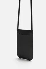 Bolso bandolera negro de cuero con bolsillo plano frontal y correa larga del mismo material.