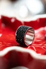 Anillo ancho de acero quirúrgico plateado, recubierto con cristales negros tipo pavé.