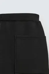 Pantalón de corte wide fit confeccionado en tejido técnico con efecto neopreno. Presenta cintura elástica ajustable con cordón, perneras anchas con costura frontal, bolsillos laterales y bolsillos traseros de plastrón.