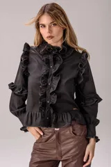 Camisa celeste con volados decorativos en los hombros, pecho, mangas y ruedo, destacados con ribetes en tono rojo. Presenta cierre frontal de botones, cuello alto y mangas largas abullonadas con puños ajustados.