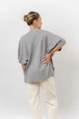 Sweater de tejido de punto color negro, con cuello semi alto y mangas cortas amplias. Presenta una silueta relajada y caída fluida.