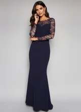 Vestido largo de fiesta color azul marino, con mangas largas de encaje y escote redondo. Presenta un diseño entallado que se ensancha suavemente hacia el ruedo.