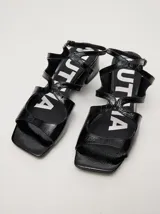 Sandalias de cuero con acabado de charol en color bordó, con diseño de tiras cruzadas, punta cuadrada y taco bloque de 4,5 cm. Incluyen correa ajustable con hebilla en el tobillo.