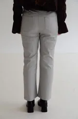 Pantalón cropped de tiro medio con acabado engomado, corte recto y bolsillos laterales. Presenta cierre frontal con botón y costuras a tono.
