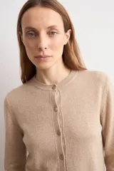 Cardigan de punto color tostado, con escote redondo, manga larga y cierre frontal de botones a tono.