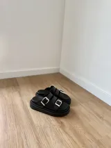 Sandalias negras con doble tira y hebillas plateadas, base chunky.