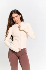 Campera deportiva de ajuste entallado, color crudo, con cuello alto, cierre frontal completo y mangas largas con orificio para el pulgar.