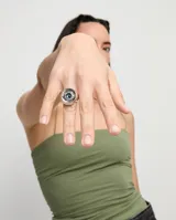 Anillo tipo sello plateado con forma de ojo y cristal facetado azul.