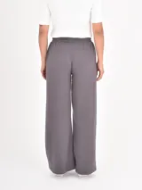 Pantalon de estilo deportivo en color gris oscuro, confeccionado en tejido de punto suave. Presenta un corte recto y holgado, cintura elástica con cordón ajustable y costuras verticales decorativas en el frente.