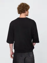 Remera de corte oversized en color beige claro, con cuello redondo y mangas de largo medio. Presenta un pequeño bordado del oso Brannan de Gap en el lado izquierdo del pecho.