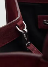 Bolso tipo shopper de piel de serraje en color bordó, con diseño estructurado, doble asa de hombro y cierre de botón magnético. Incluye forro interior de algodón y bolsillo con cierre de cremallera.