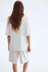 Blazer blanco de sarga con manga corta, botonadura sencilla con un botón, solapas de muesca y bolsillos delanteros ribeteados.