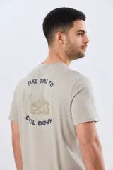 Remera gris oscuro de manga corta y cuello redondo, con un estampado gráfico en la espalda que incluye un paisaje de montaña y la leyenda "Take time to chill vibes cool down".