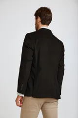 Blazer de pana color marrón oscuro, con cierre frontal de dos botones, solapas clásicas y bolsillos laterales con solapa. Presenta un diseño estructurado y elegante.
