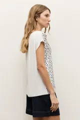 Blusa de manga corta color crudo con estampado de lunares negros y escote en V.