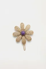 Hebilla para el pelo metálica dorada con diseño de flor y piedra sintética violeta en el centro.