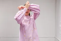 Vestido de algodón color lila con estampado floral sutil en tonos amarillos, de silueta amplia y mangas largas voluminosas con detalle de tablas.