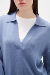 Sweater de punto color azul, con cuello polo y escote en V, de manga larga y diseño holgado.
