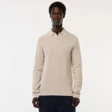 Suéter de punto color beige claro, con cuello polo y tapeta de tres botones. Presenta un tejido texturizado de punto fantasía y puños y bajo acanalados.