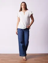 Blusa blanca de modal Rio & Rian con cuello a la base, escote en V con aplique metálico y mangas cortas con volados en capas.