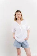 Camisa color topo confeccionada en lino, de corte holgado, con escote en V abotonado, bolsillo frontal y mangas 3/4 arremangables.