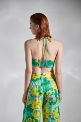 Top strapless con estampado floral en tonos verde y amarillo, con tirantes finos al cuello y detalle de nudo en el centro del busto.