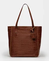 Bolso shopper negro de cuero con textura de cocodrilo, doble asa de hombro y dije colgante rectangular.