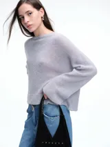 Sweater de punto negro con lentejuelas sutiles, de corte holgado, hombros caídos y mangas largas con terminación acampanada.