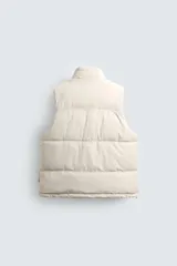 Chaleco acolchado de corte regular con acabado efecto engomado. Presenta cuello subido, cierre frontal con cremallera y bolsillos laterales con cierre. Incluye bajo ajustable con elástico en los laterales.