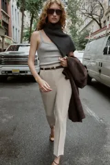 Pantalón de tiro alto y corte tobillero, confeccionado en tejido de aspecto denim oscuro. Presenta diseño de pinzas frontales, bolsillos laterales y cierre frontal con cremallera, botón y gancho. Incluye un cinturón fino a tono con hebilla metálica dorada.