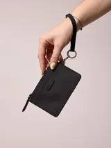 Billetera de poliuretano color celeste, con cierre de cremallera y correa de mano.