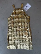 Vestido corto de diseño de autor, confeccionado artesanalmente mediante una estructura de piezas cuadradas de cuero metalizado dorado unidas por remaches metálicos, con escote halter.