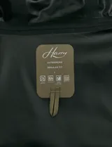 Gabardina con capucha de corte recto y largo medio. Cuenta con cierre frontal engomado, cartera con botones a presión, bolsillos laterales y tejido repelente al agua y al viento.