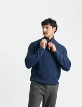 Sweater de punto inglés color verde, con cuello alto y cierre frontal parcial metálico. Diseño de manga larga con puños y ruedo acanalados.