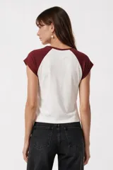 Remera al cuerpo con diseño raglán, color blanco en el torso y azul marino en las mangas cortas y el cuello. Cuenta con un estampado frontal de temática de tenis con las inscripciones "Portofino Tennis" y "Summer Italia".