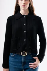 Cardigan de punto acanalado color negro, con cuello camisero, cierre frontal de botones y dos bolsillos delanteros aplicados.