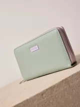 Billetera de poliuretano texturizado color rosado con cierre perimetral y logo metálico al frente.