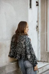 Camisa de lino con estampado abstracto en tonos oscuros, presenta volados decorativos con puntilla blanca en el frente y hombros, cuello clásico y mangas largas.