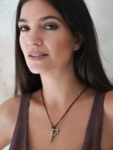 Collar con cordón de cuero y dije en forma de letra fabricado en bronce con acabado rústico.