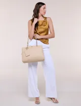Cartera de hombro de cuero sintético beige, con estructura tripartita de compartimento central con cierre y dos compartimentos laterales con broche magnético. Posee asas dobles con detalles de cadena metálica dorada y un tarjetero independiente desmontable.