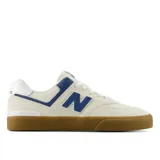 Championes New Balance Numeric 574, modelo de skate en color beige con detalles en azul y suela de goma color caramelo. Confeccionados en gamuza y malla, presentan el logo N característico en los laterales.