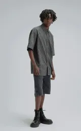 Camisa de manga corta con calce oversize, confeccionada en algodón con bordado tipo broderie y acabado con efecto desgastado. Presenta cuello clásico y cierre frontal con botones.